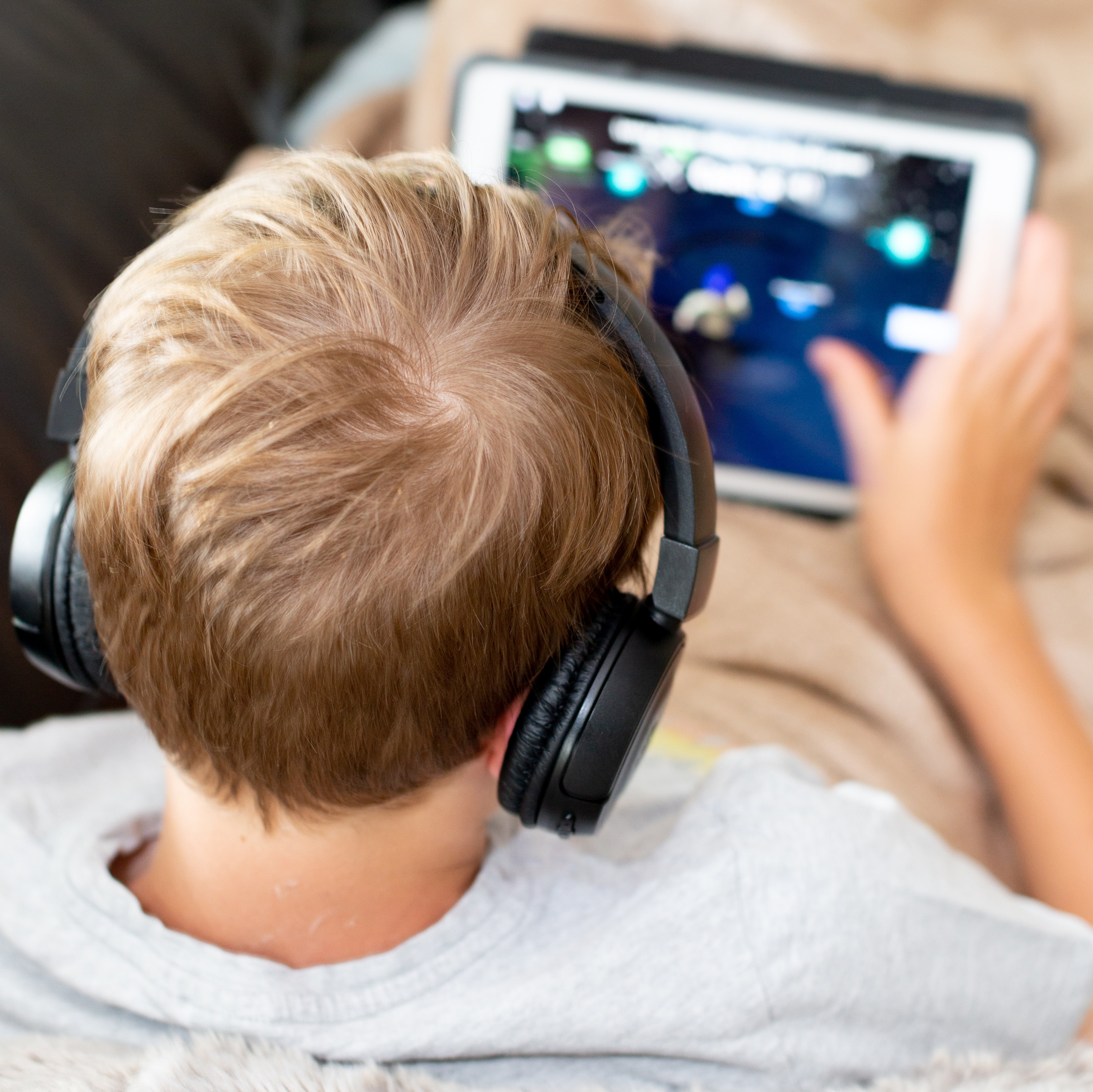 boy in shirt playing on white iPAD