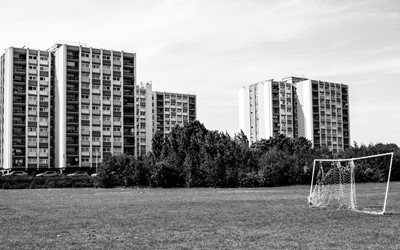 black and white photo of block of flats overlooking park 