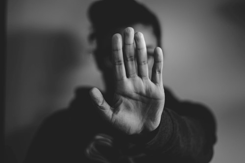 woman with hand pushed out in front of her face